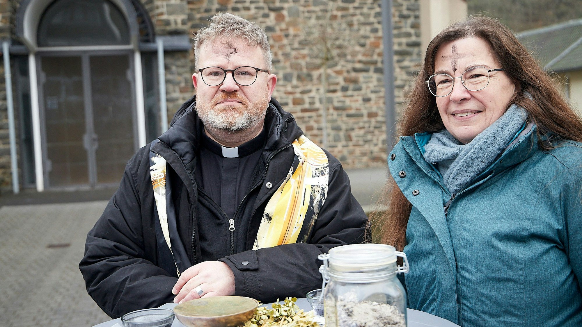 Pfarrvikar Michael Krosch und Gemeindereferintin Dagmar Goffert stehen vor der Kirche St. Anna in Hellenthal.