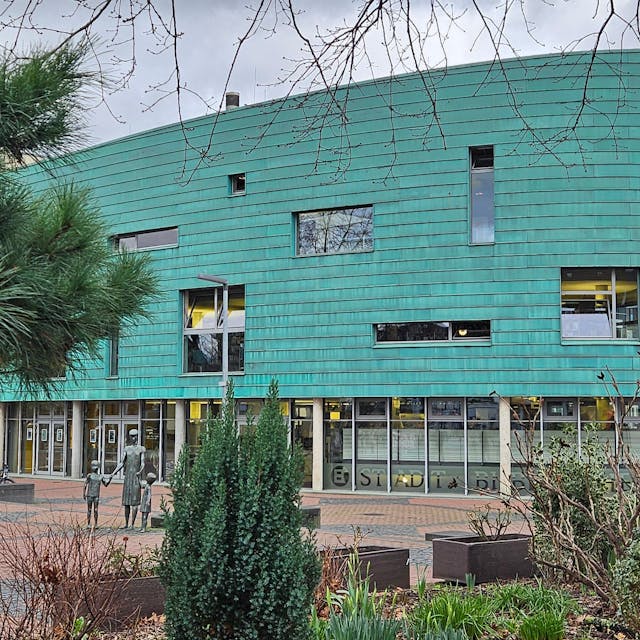Ein großes Gebäude in der Form eines Schiffbugs mit grüner Fassade.