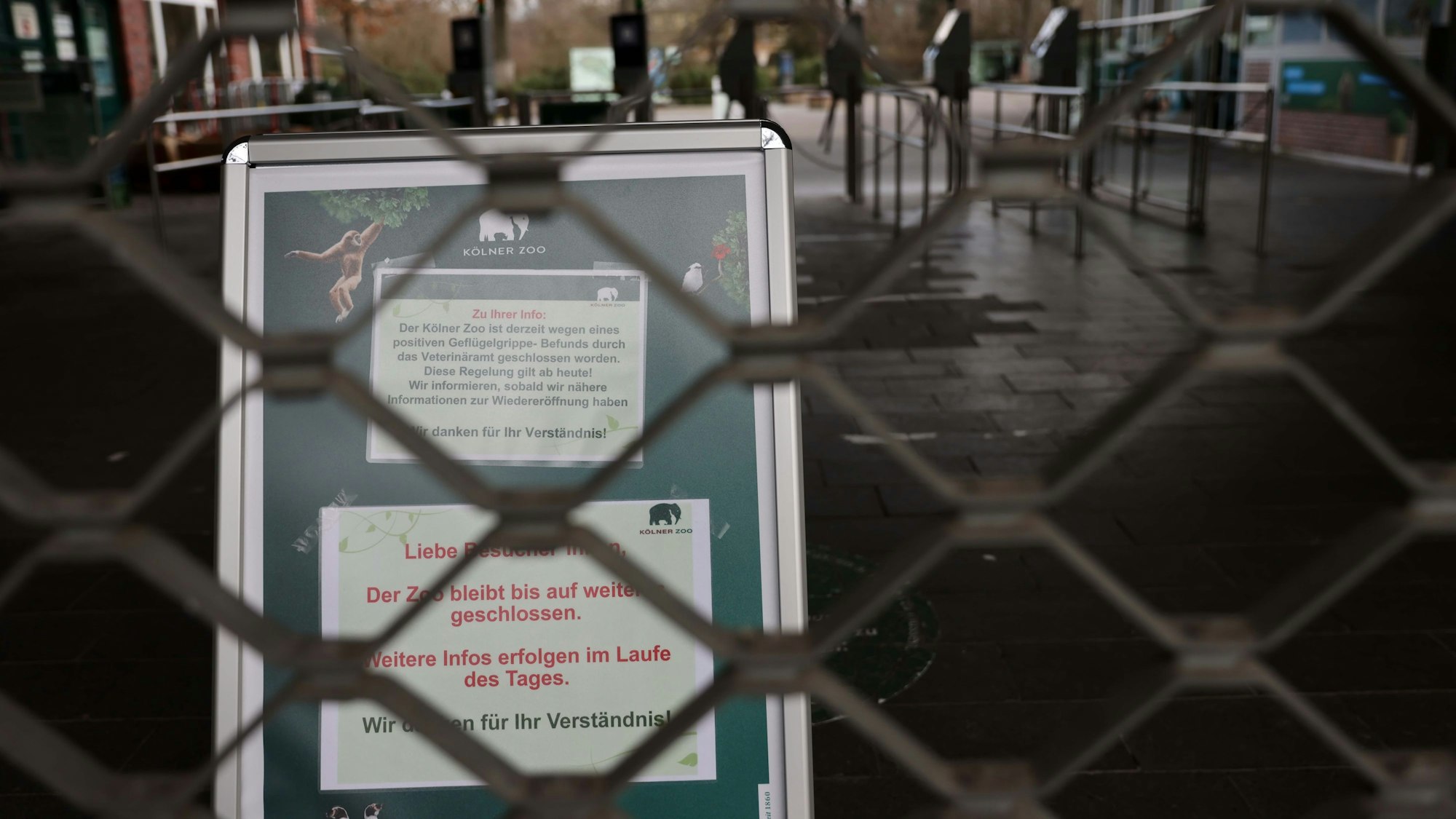 Der Zoo in Köln ist derzeit wegen des Ausbruchs der Vogelgrippee geschlossen. Hinter dem geschlossenen Gitter steht eine Hinweistafel.