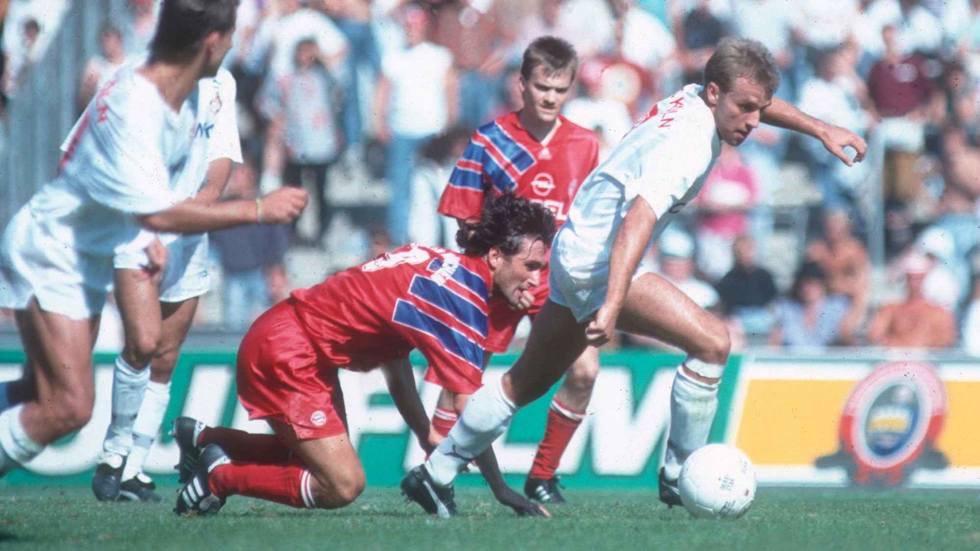 Ganz in Weiß gekleidete Spieler des 1. FC Köln kämpfen mit ihren in Rot spielenden Gegnern vom FC Bayern München um den Ball.