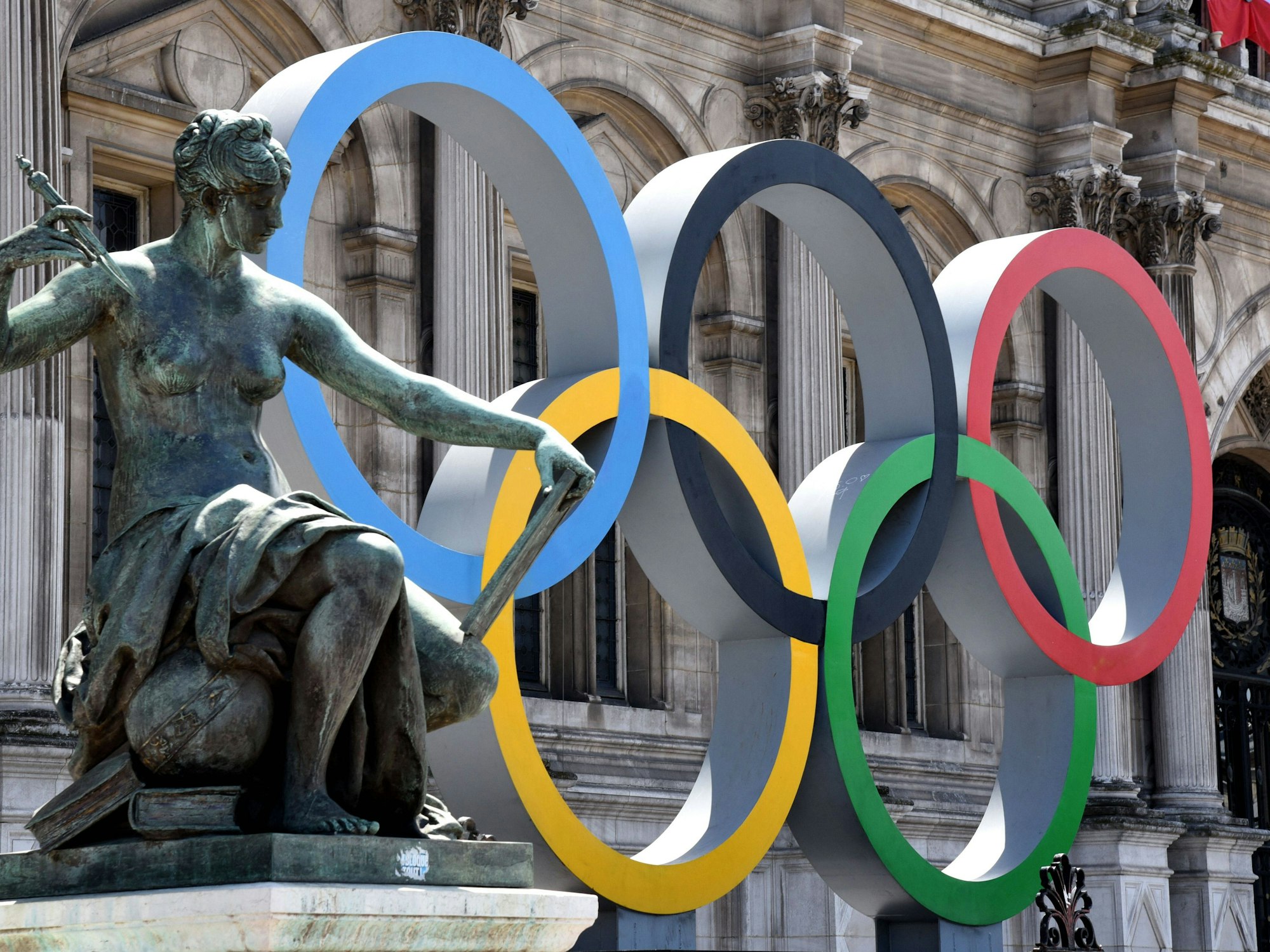 Die Olympischen Ringe vor dem Pariser Rathaus, links daneben eine weibliche Statue