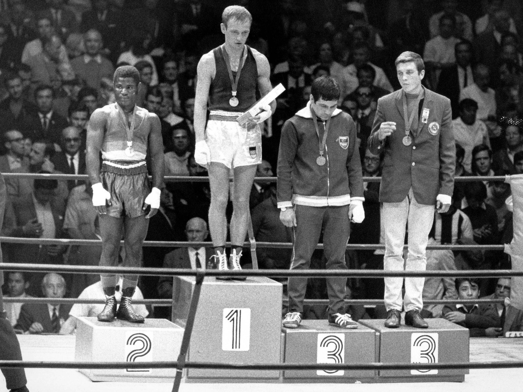 Die Siegerehrung beim Boxen im Ring, Manfred Wolke (M., DDR) gewinnt vor Joseph Bessala (li., Kamerun), Mario Guilloti (2.v.re.) und Wladimir Musalimow (UdSSR), im Hintergrund Zuschauer und Zuschauerinnen.