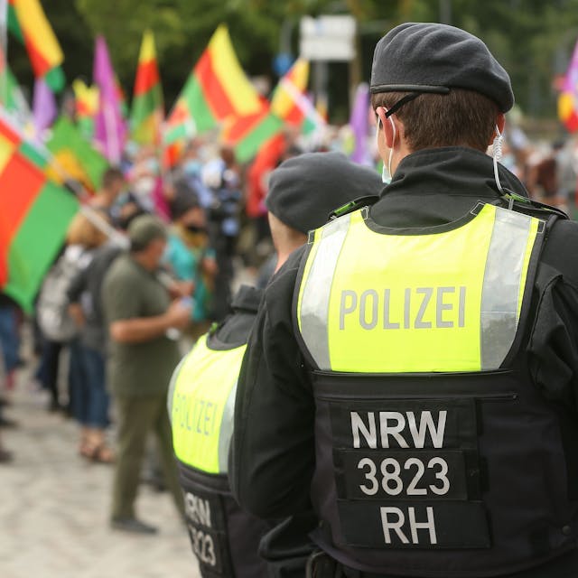 Im Sommer 2021 hatten Kurden auf dem Ottoplatz in Deutz demonstriert. Nun steht eine Großkundgebung auf dem Ottoplatz an. Zu sehen ist ein Polizist und Demonstrierende mit Fahnen.&nbsp;