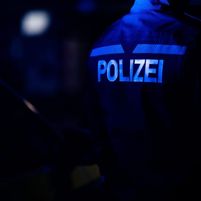 Ein Polizist steht neben einem Polizeiauto.
