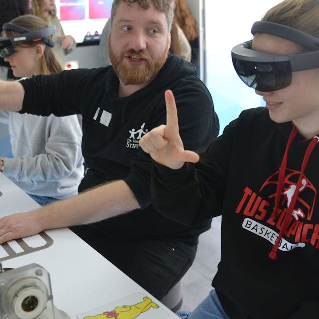 Eine Schülerin des Zülpicher Franken-Gymnasiums trägt eine VR-Brille. Mit ihren Händen bewegt sie virtuelle Gegenstände, die ohne Brille nicht sichtbar sind.