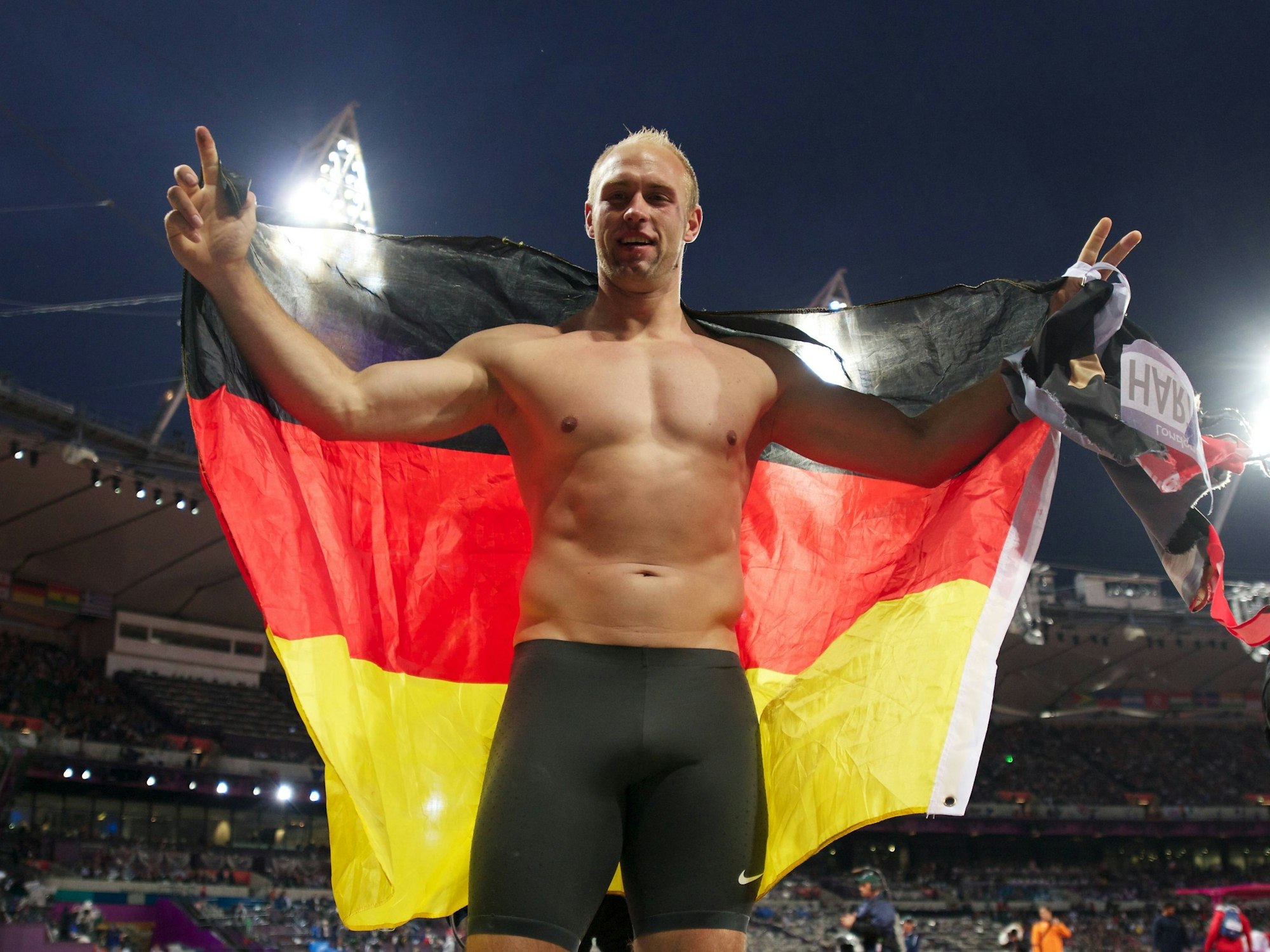 Robert Harting feiert oberkörperfrei und mit Deutschlandflagge in der Hand seine Goldmedaille im Diskus.