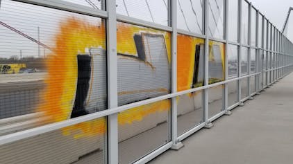Ein gelbes Graffiti auf einer Glasscheibe der Leverkusener Brücke.&nbsp;