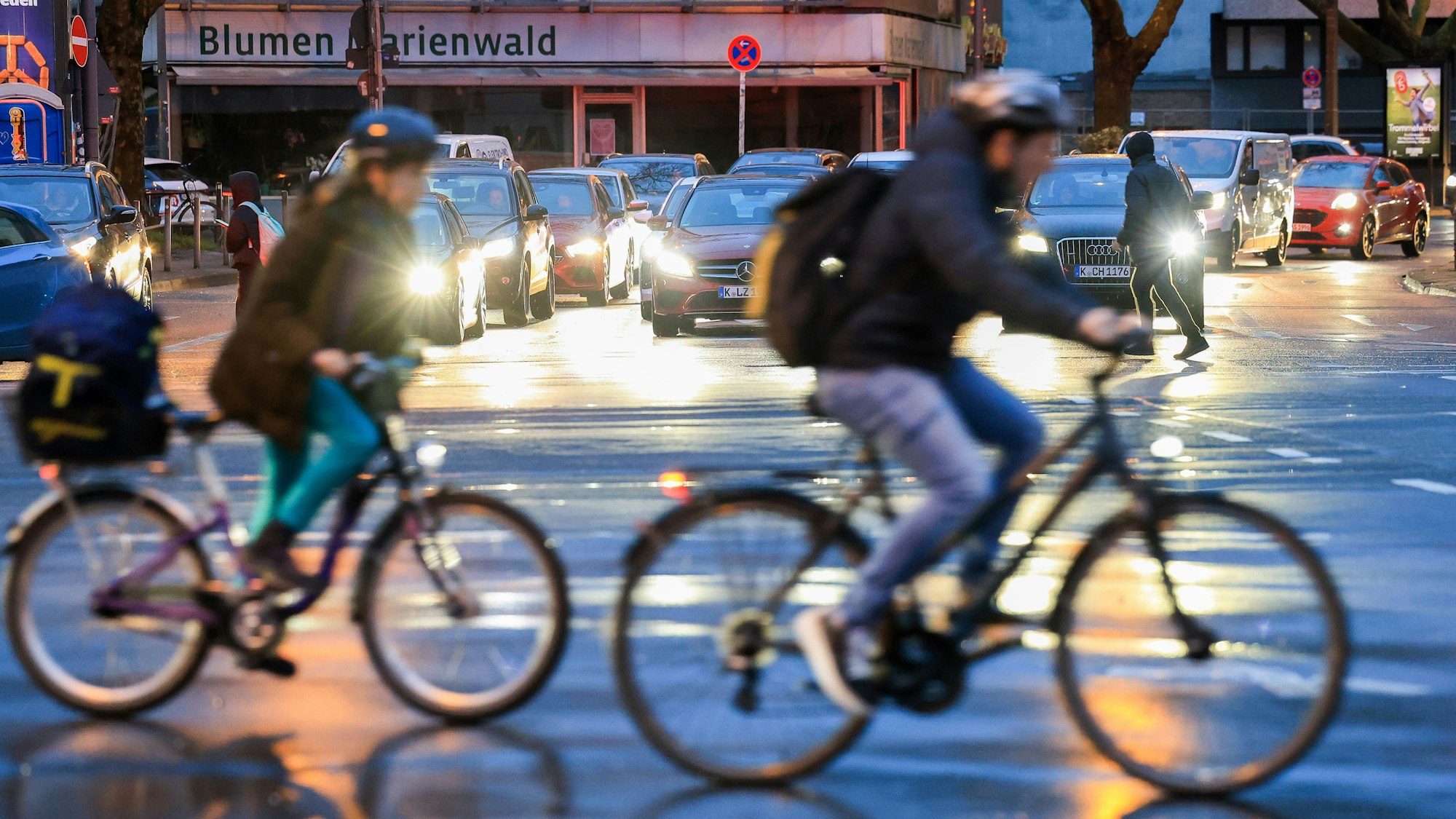 Zwei Fahrradfahrer überqueren hintereinander eine Straße.