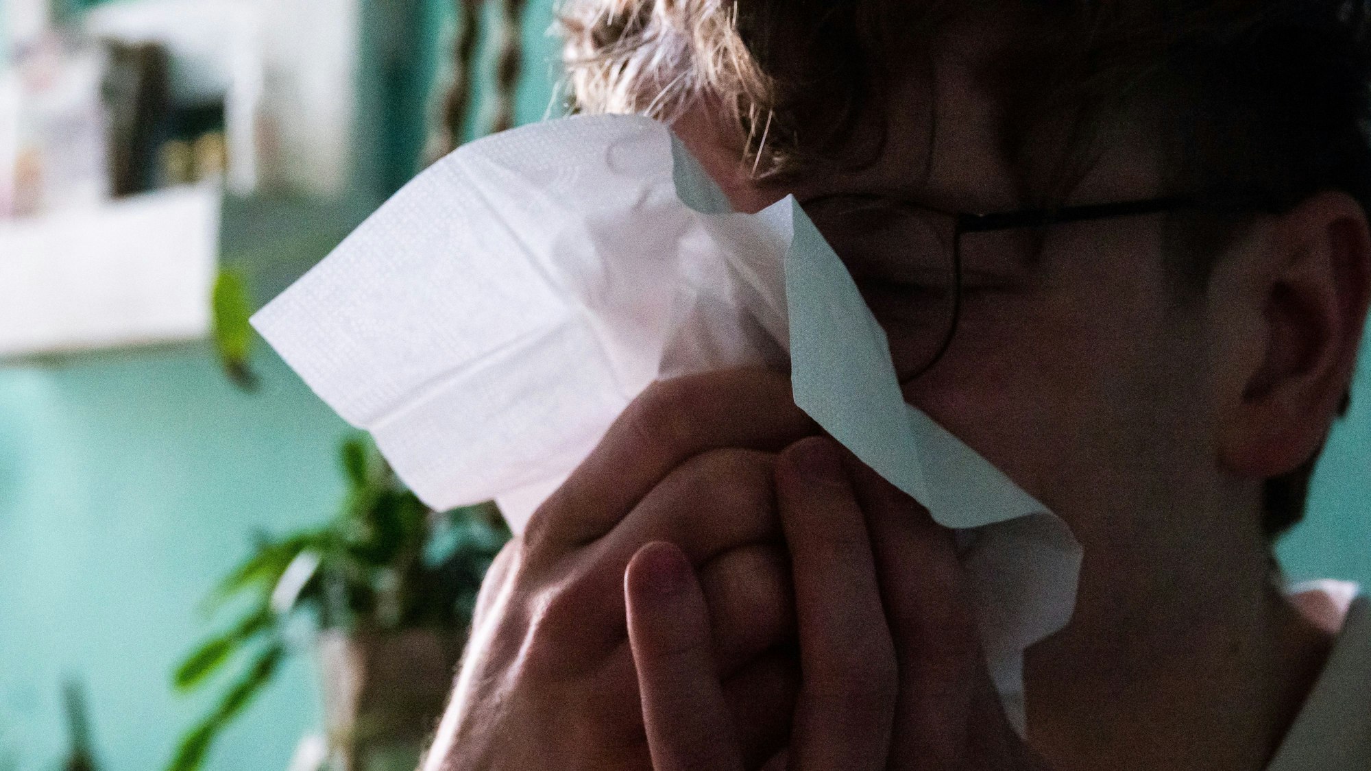 Ein Mann putzt sich mit einem Taschentuch die Nase (gestellte Szene).