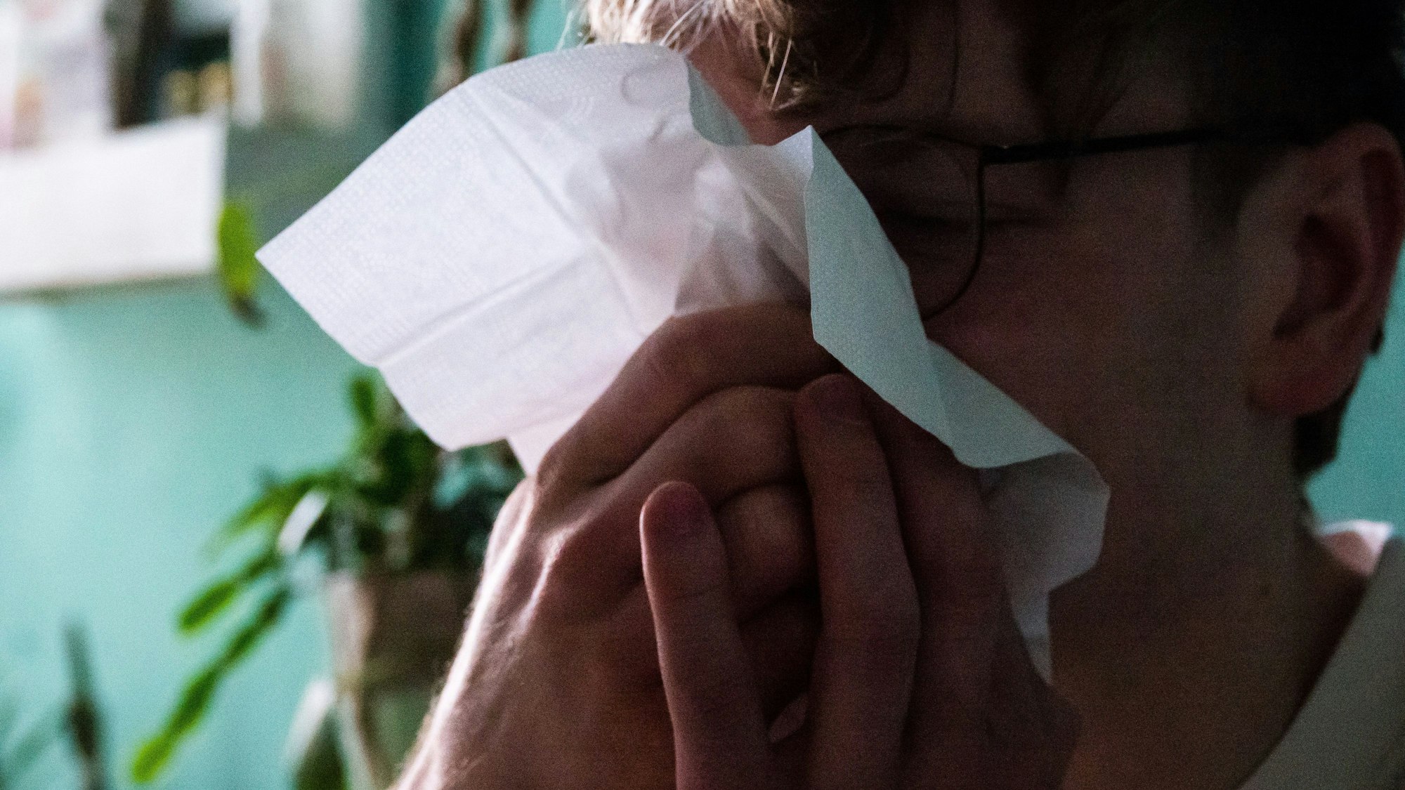 Ein Mann putzt sich mit einem Taschentuch die Nase.