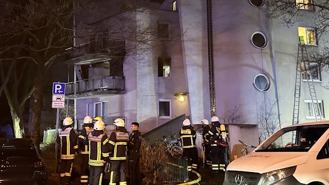 Einsatzkräfte der Kölner Feuerwehr stehen vor dem Haus in der Tiefentalstraße. in Mülheim, wo das Feuer ausbrach.