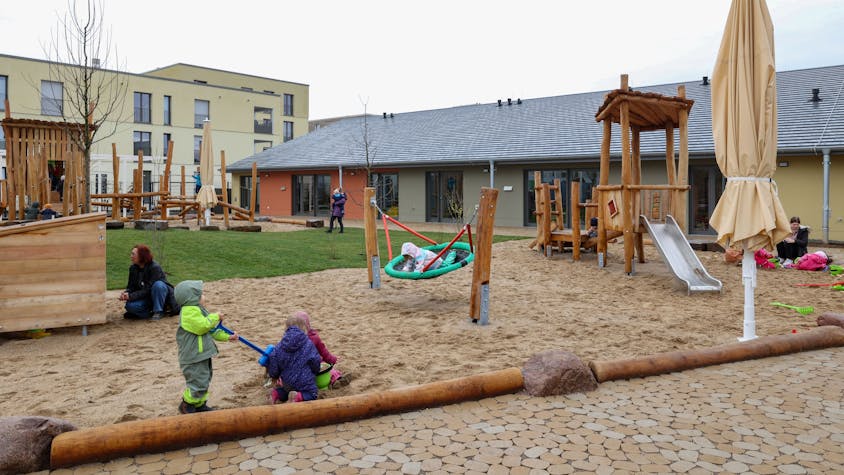 Kinder spielen auf dem Außengelände einer Kindertagesstätte.