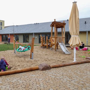 Kinder spielen auf dem Außengelände einer Kindertagesstätte.
