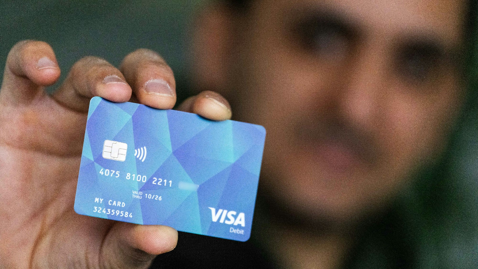Ein Geflüchteter hält eine Debitkarte in der Hand (Symbolbild).