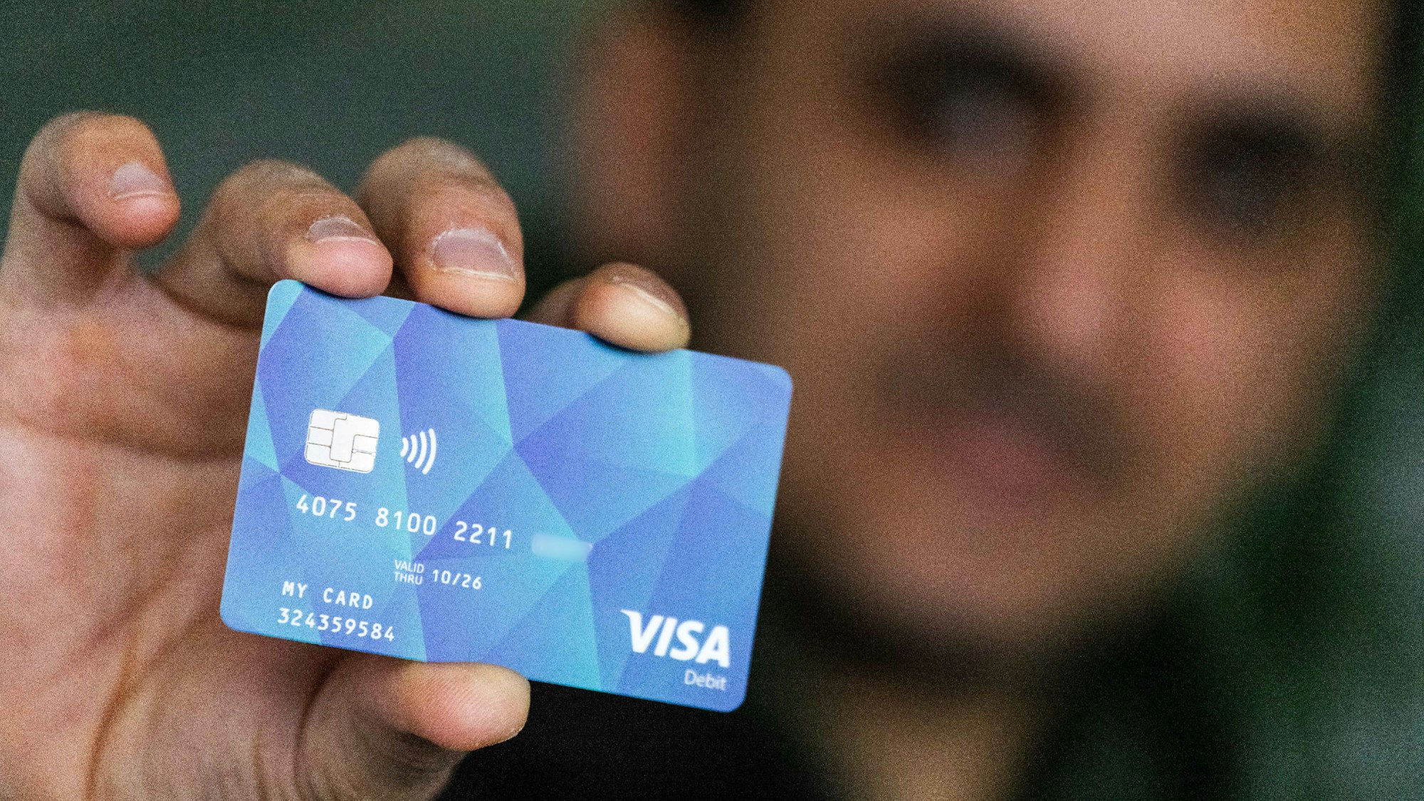 Ein Geflüchteter hält eine Debitkarte in der Hand. (Symbolbild)