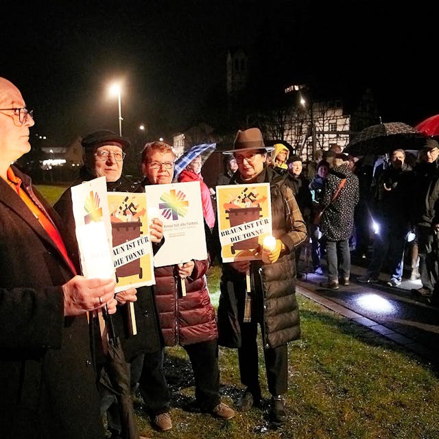 Teilnehmer einer Mahnwache gegen rechts halten Plakate vor dem Körper.