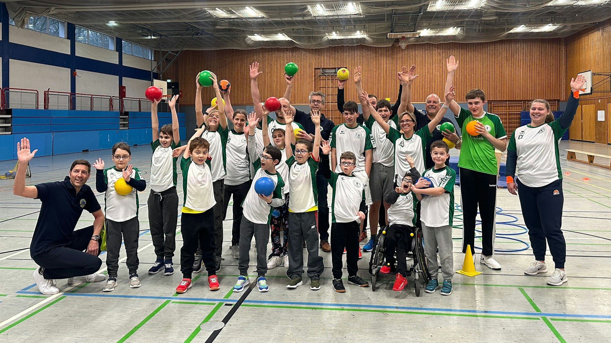 Die Mannschaft der Handballgruppe für Kinder mit Handicap streckt die Hände in die Luft.