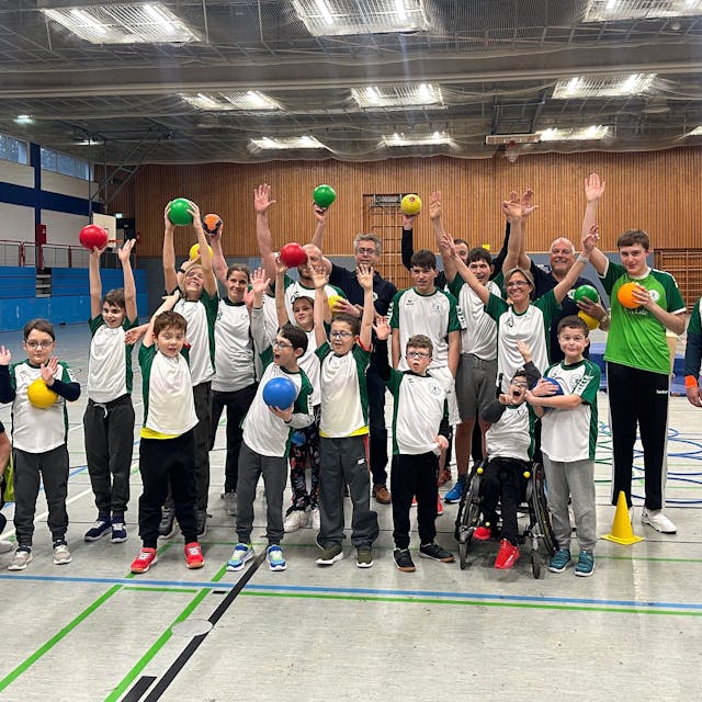 Die Mannschaft der Handballgruppe für Kinder mit Handicap streckt die Hände in die Luft.&nbsp;