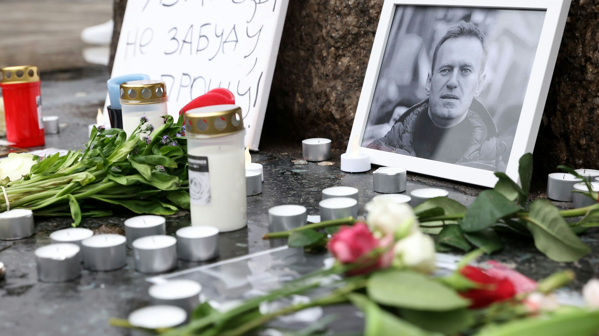 Neben Porträts des verstorbenen Alexej Nawalny 
liegen Blumen, stehen Kerzen.
