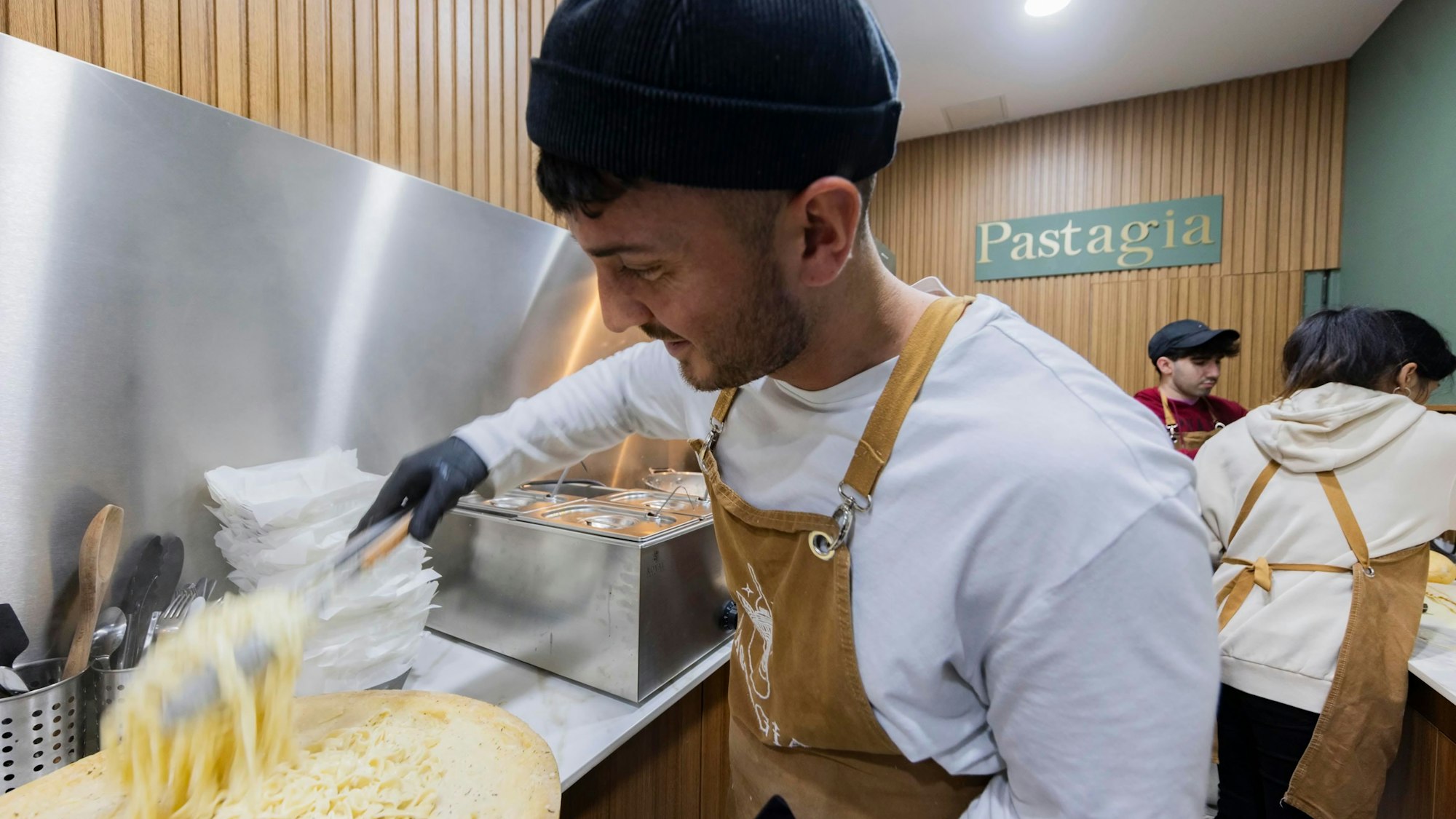 Fuat Aydin, einer der Gründer von Pastagia, schwenkt Pasta im Parmesanlaib.