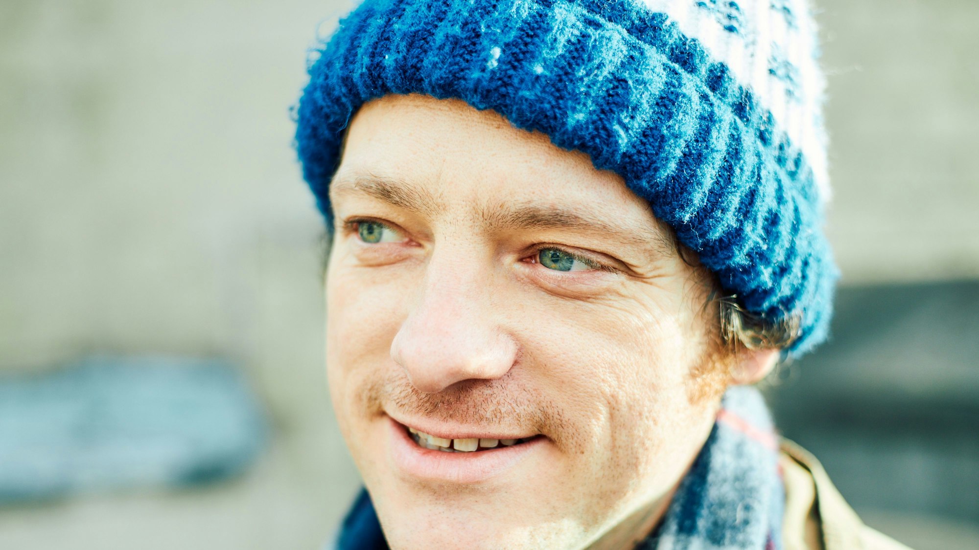 Kurt Tallert trägt eine blaue Mütze und lächelt