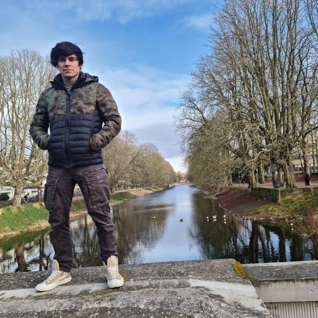 Ein junger Mann steht auf einer Beton-Brüstung, im Hintergrund ist der Lindenthaler Kanal zu sehen.