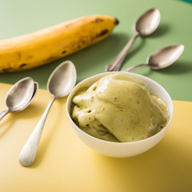 Matcha-Nice Cream in einer Schale, daneben kleine Löffel und eine Banane