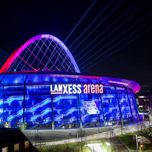 Illumination der Lanxess-Arena zur Handball-Europameisterschaft im Januar. Die Halle erstrahlt in blauem Licht, der Bogen ist rosa angestrahlt.&nbsp;