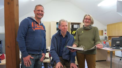 Eine Frau und zwei Männer in einem Großraumbüro