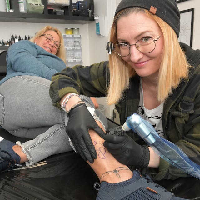 Die Tattoo-Künstlerin Rebekka Behr sticht Anja Schwerm das Organspende-Symbol unter die Haut. 
