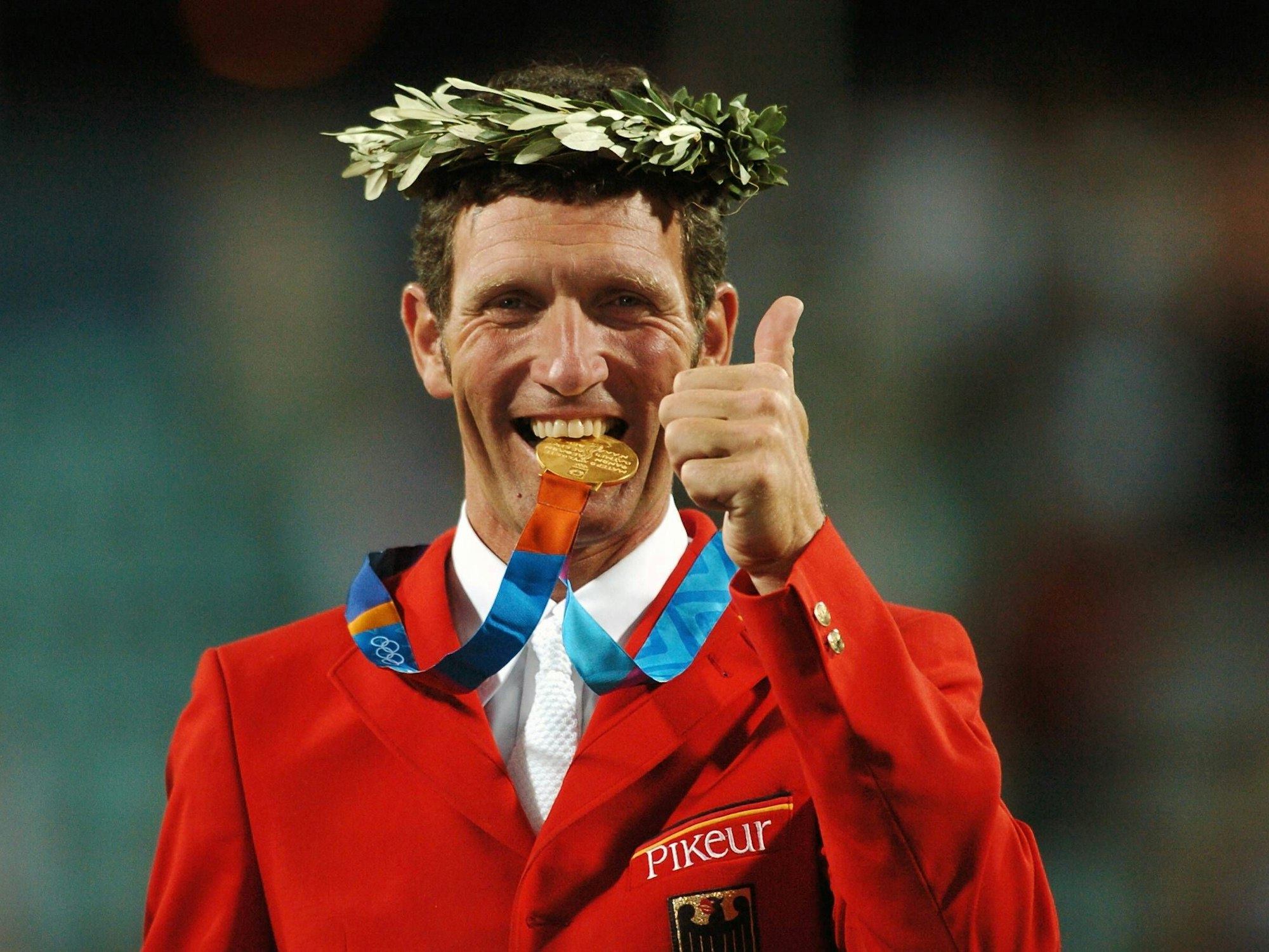 Ludger Beerbaum (Deutschland) - Olympiasieger in der Teamwertung bei den Olympischen Sommerspielen 2004 - beißt glücklich in seine Goldmedaille