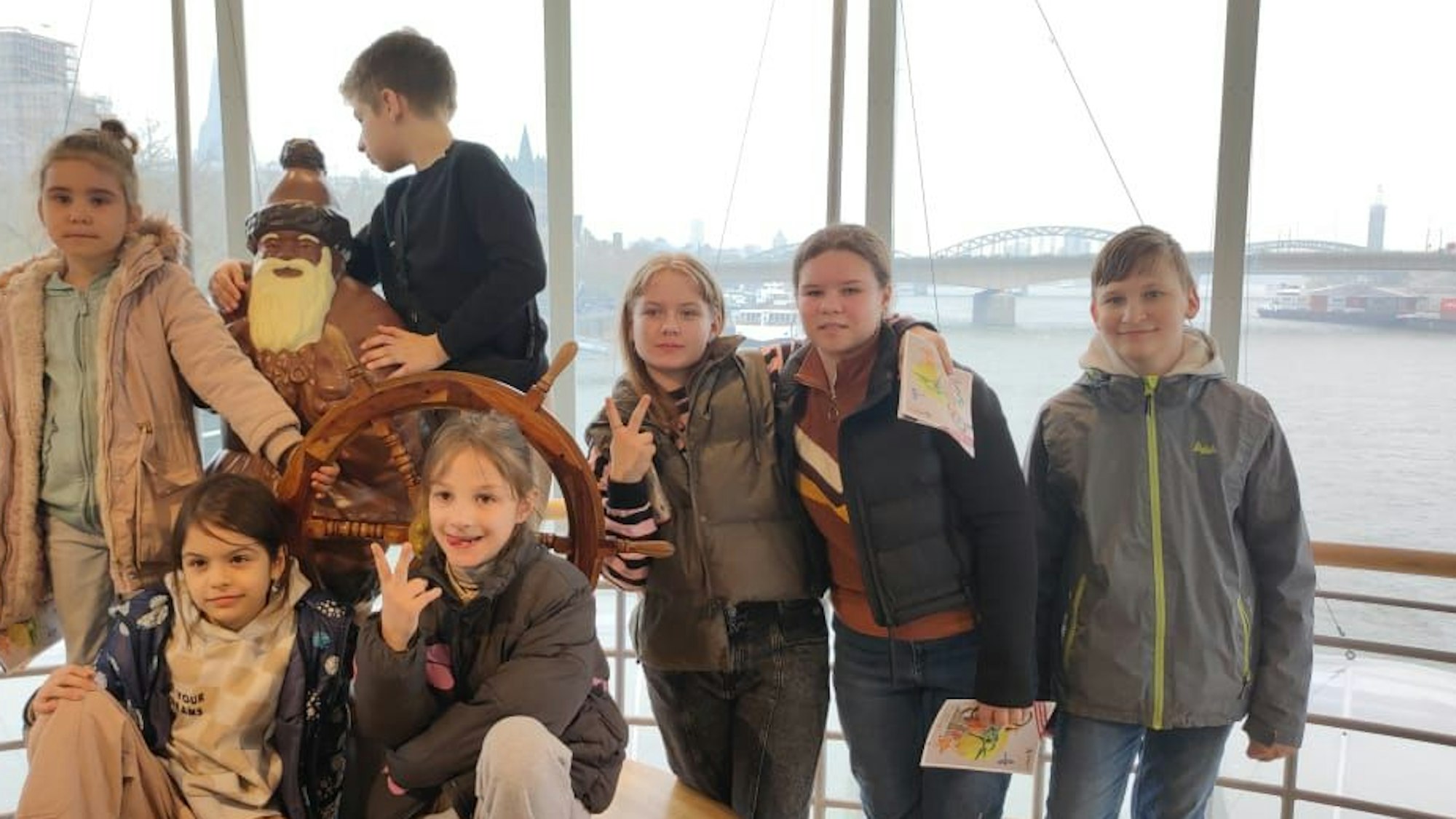 Sieben gehörlose und geflüchtete Kinder des Kölner Vereins Shahrzad stehen hinter einem Ruder im Kölner Schokoladenmuseum
