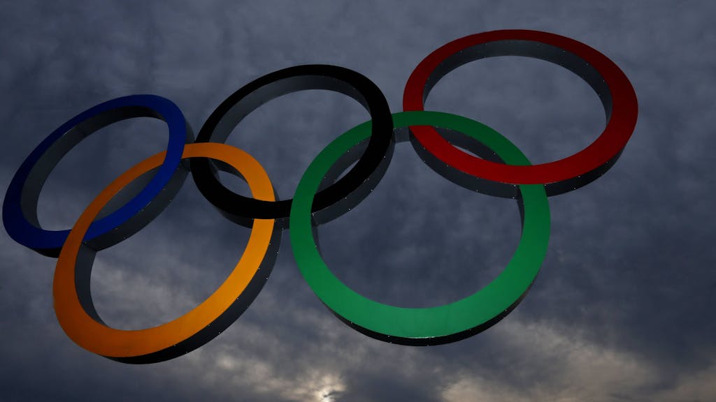 Olympische Ringe vor dunklen Wolken