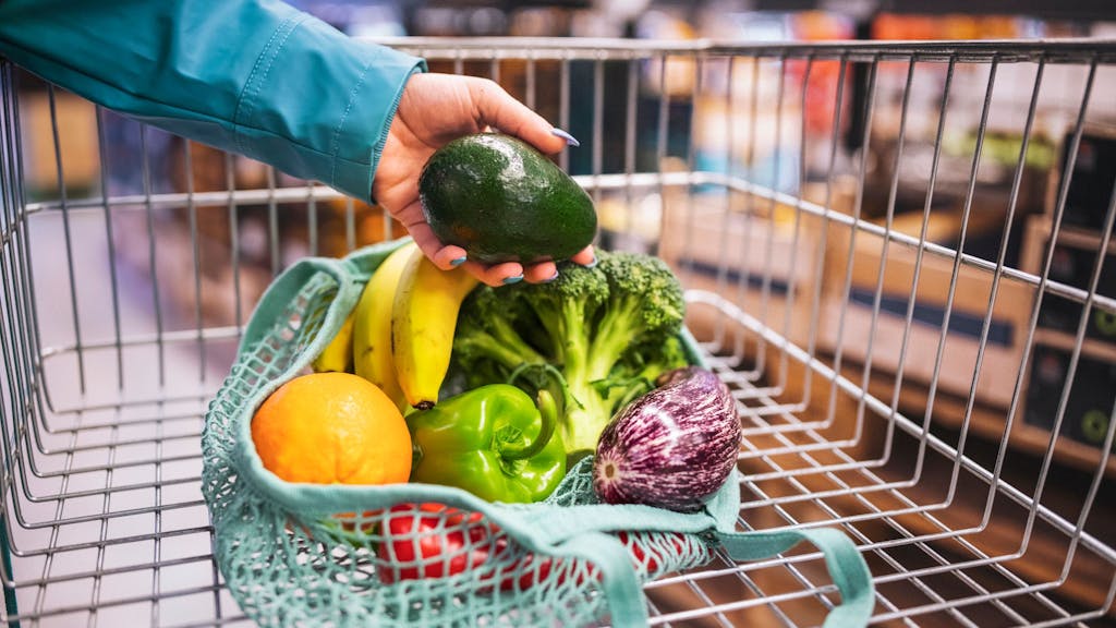 Ein Einkaufsnetz mit Gemüse in einem Einkaufswagen.