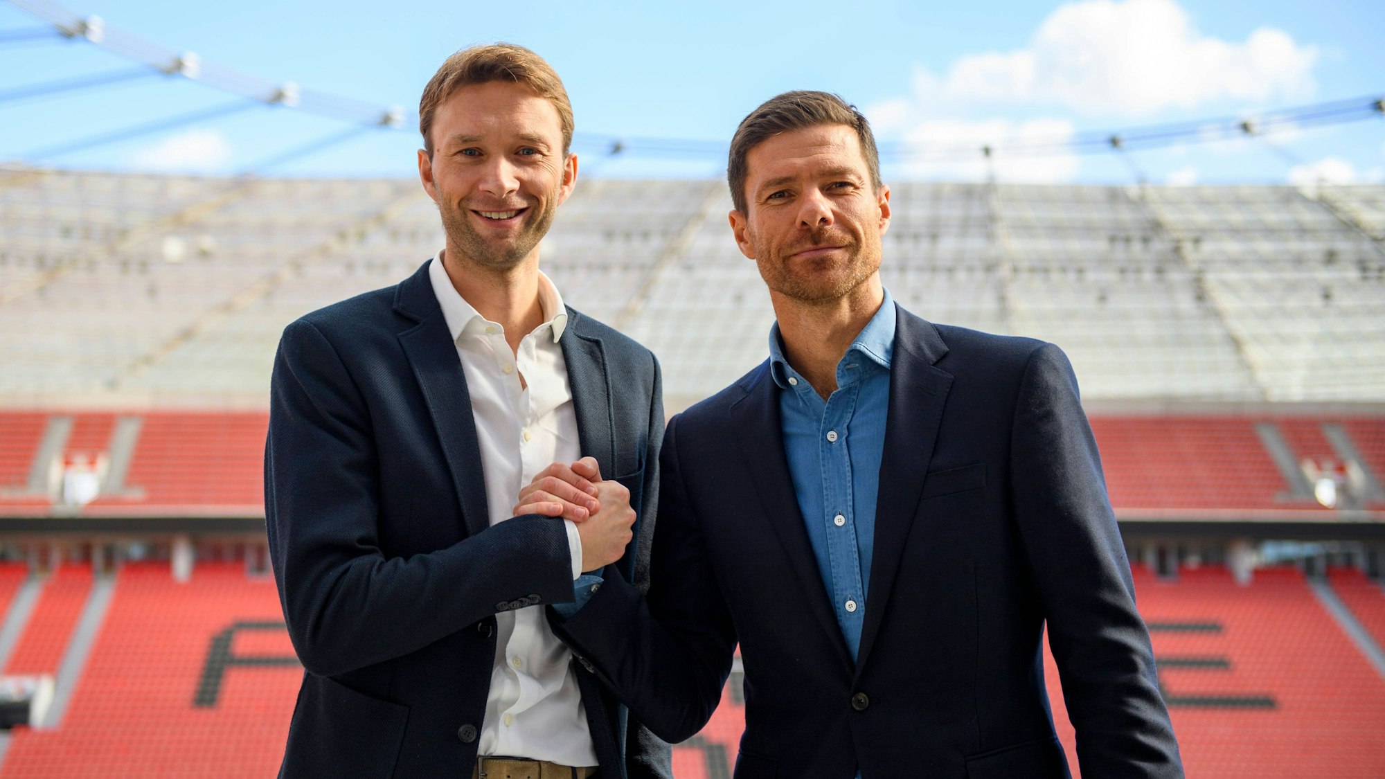 Leverkusens Sportdirektor Simon Rolfes und Leverkusens Cheftrainer Xabi Alonso auf der Tribüne im Stadion.