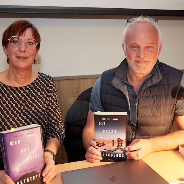 Ein Mann und eine Frau, Übersetzerin Franziska Weyer und der Schweizer Autor Marc Voltenauer, sitzen an einem Tisch. Beide halten ein Buch in der Hand.