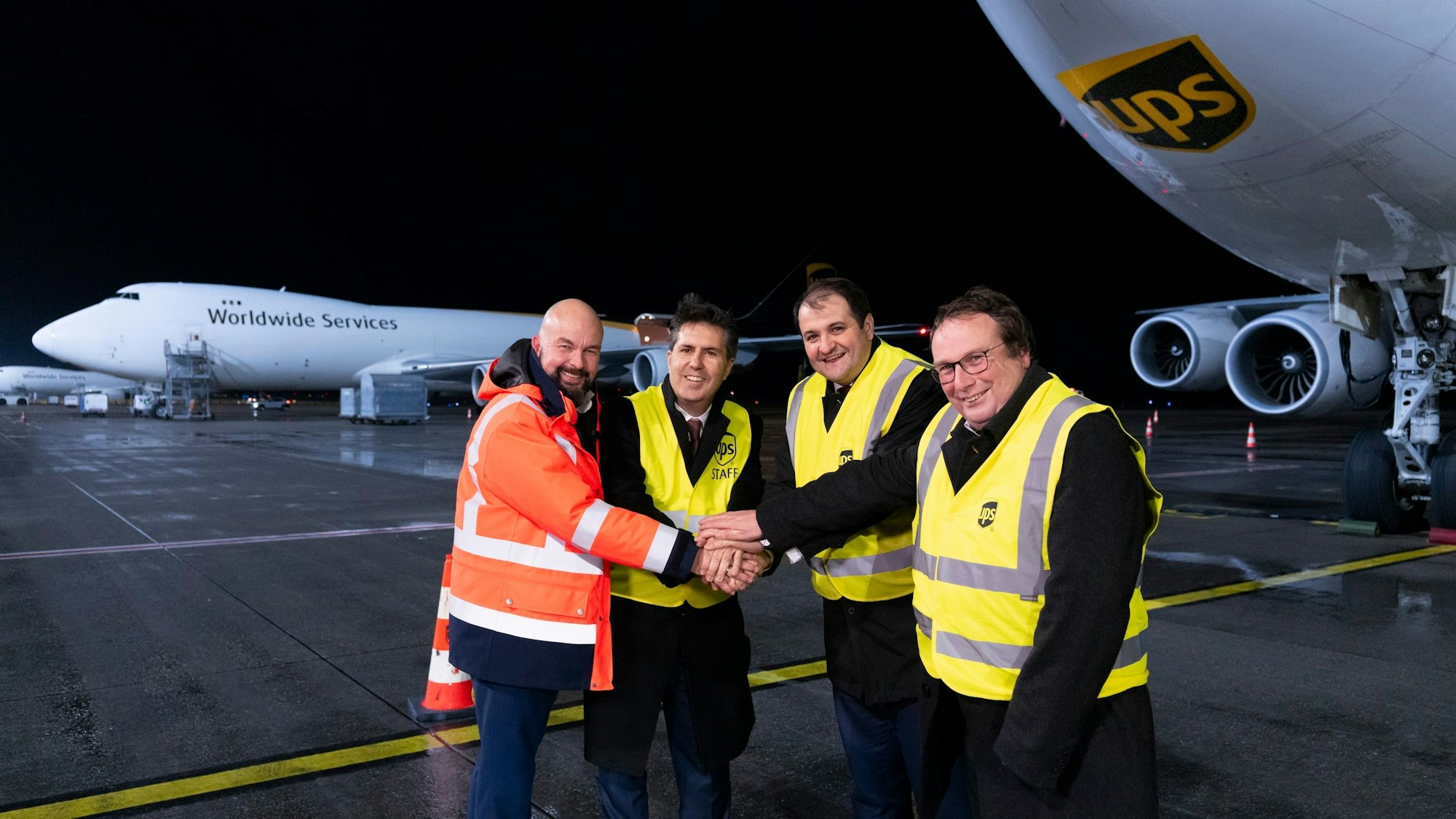Flughafenchef Thilo Schmid (v.l.), UPS-Europachef Daniel Carrera und die beiden NRW-Minister Nathanael Liminski und Oliver Krischer vor einer Boeing 747-8 auf dem Rollfeld in Köln/Bonn.