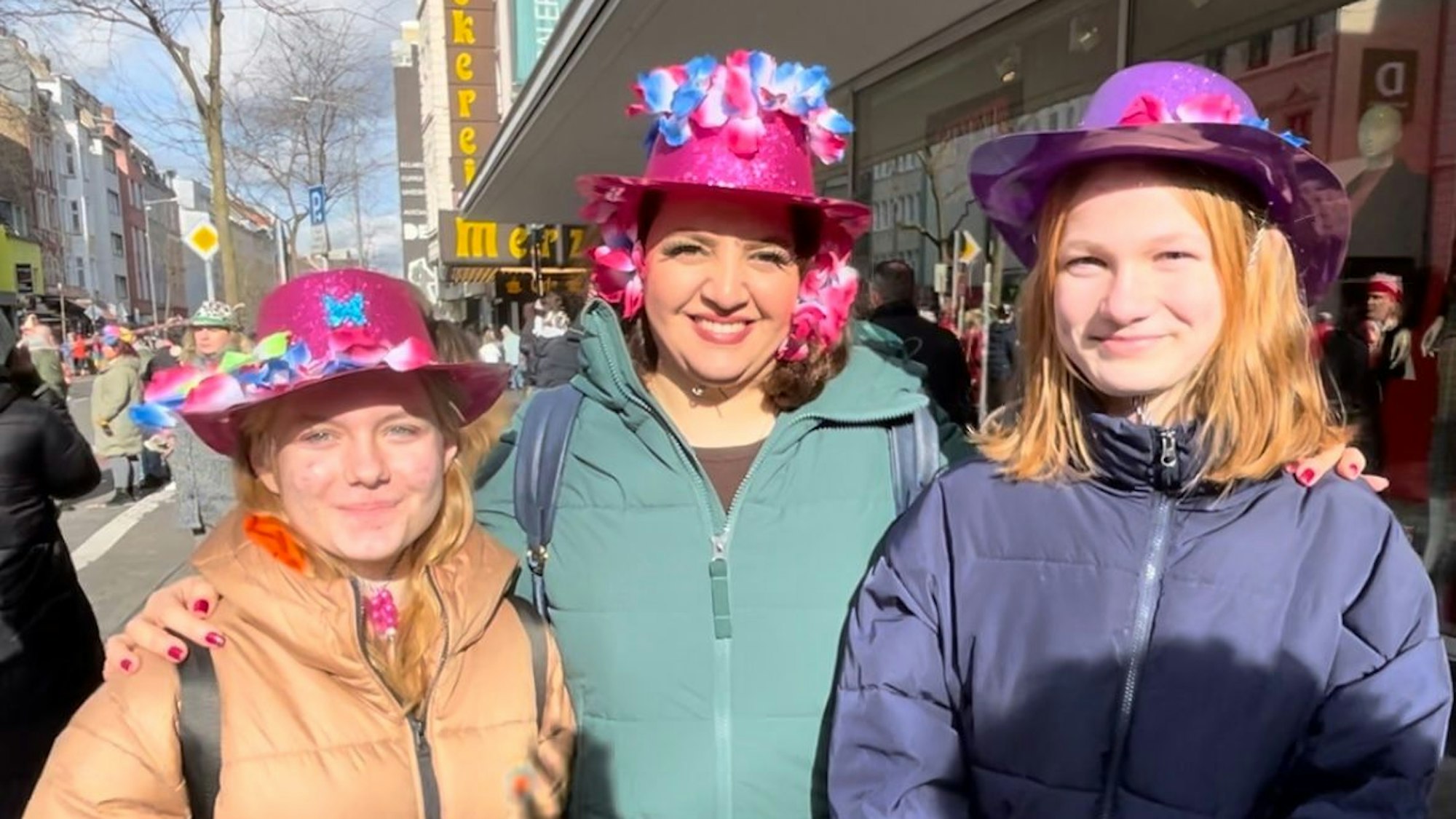 Die beiden 13-jährigen gehörlosen geflüchteten Teenagerinnen Polina und Chloé und die Kindergruppenleiterin Arezu Sadeghi tragen bunte Karnevalshüte.