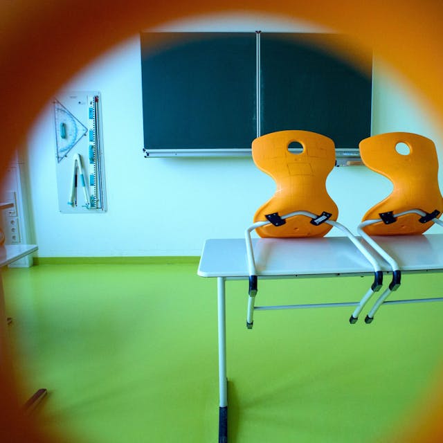 Stühle stehen in einem leeren Klassenzimmer einer Sekundarschule auf einem Tisch.