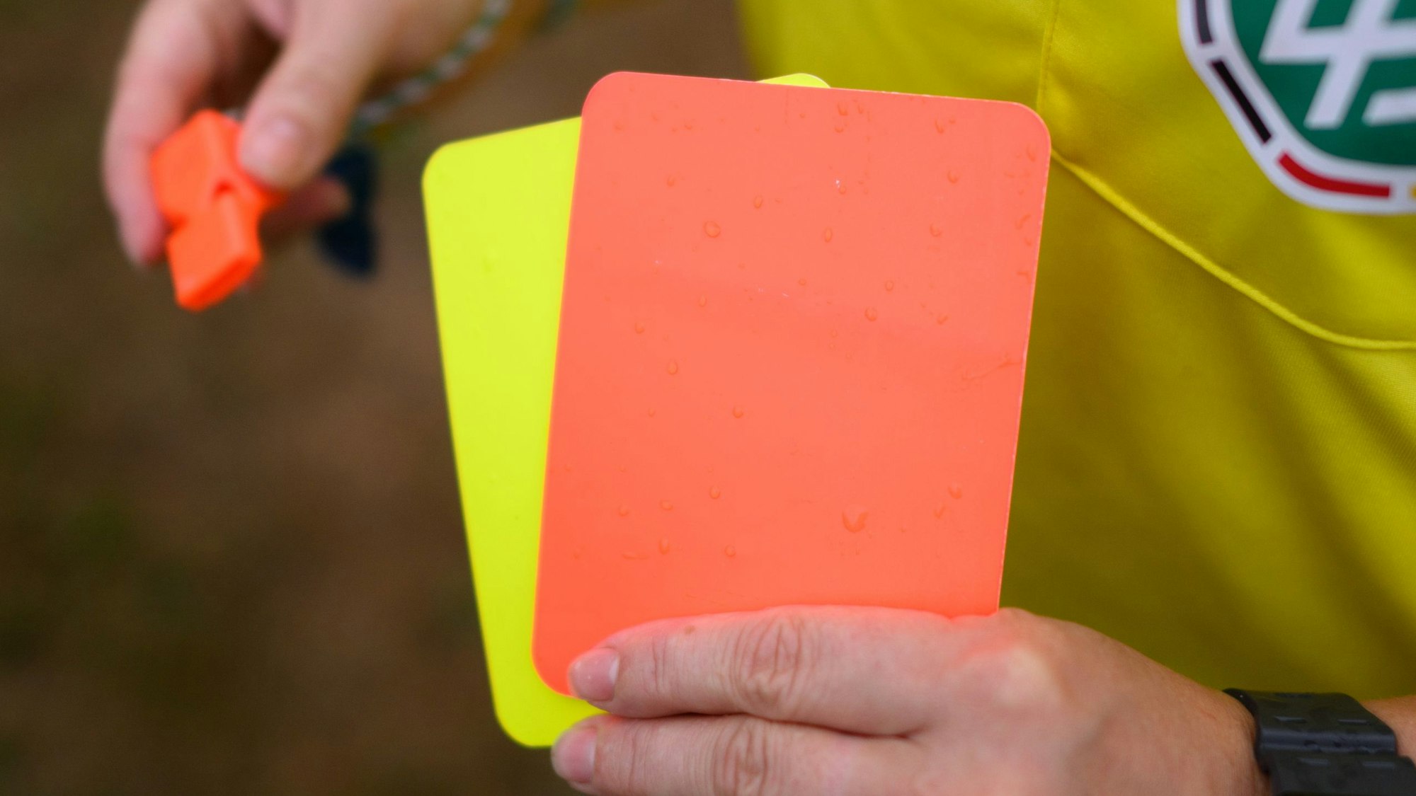 Eine Schiedsrichterin hält eine gelbe und eine rote Karte in der Hand.