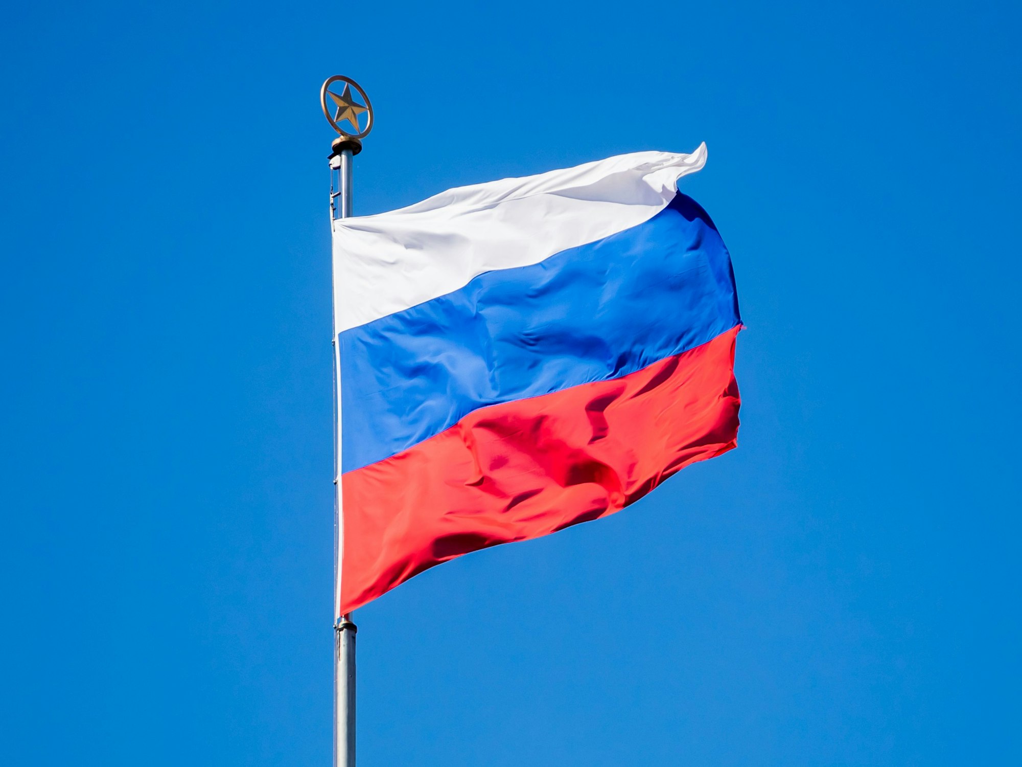 Die Flagge Russlands vor blauem Himmel.
