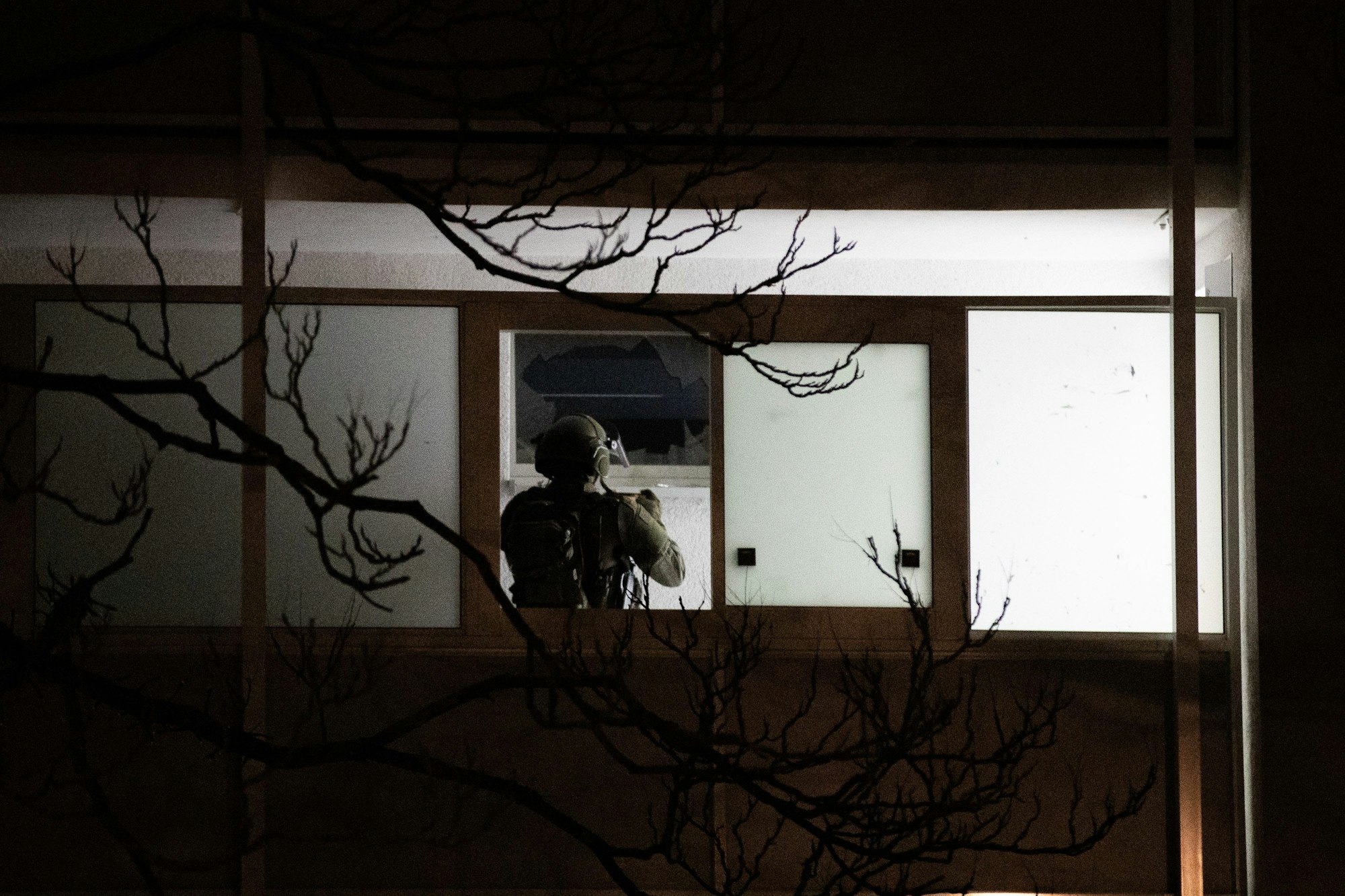 Einsatz in Düsseldorf: Ein Polizist steht vor einer zerbrochenen Fensterscheibe und fotografiert die Einsatzstelle.