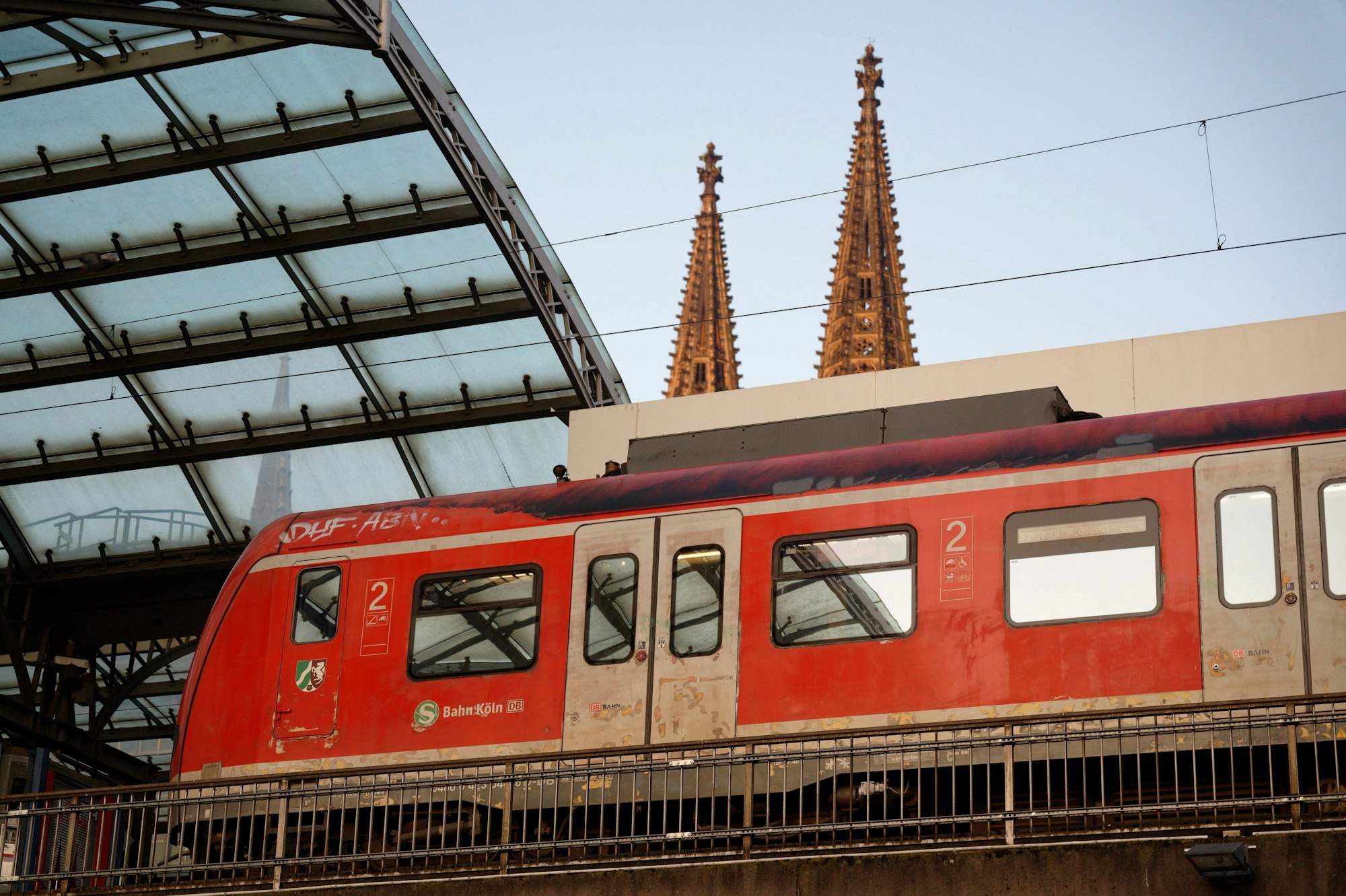 Eine S-Bahn steht im Hauptbahnhof in Köln. Im Hintergrund sind die Domspitzen zu sehen.