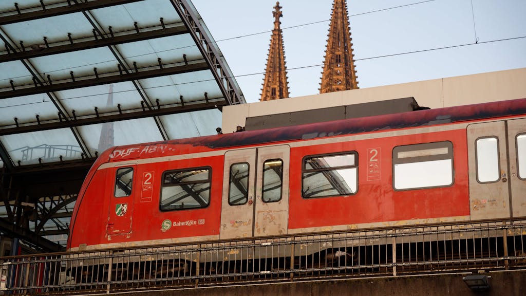 Eine S-Bahn steht im Hauptbahnhof in Köln. Im Hintergrund sind die Domspitzen zu sehen.