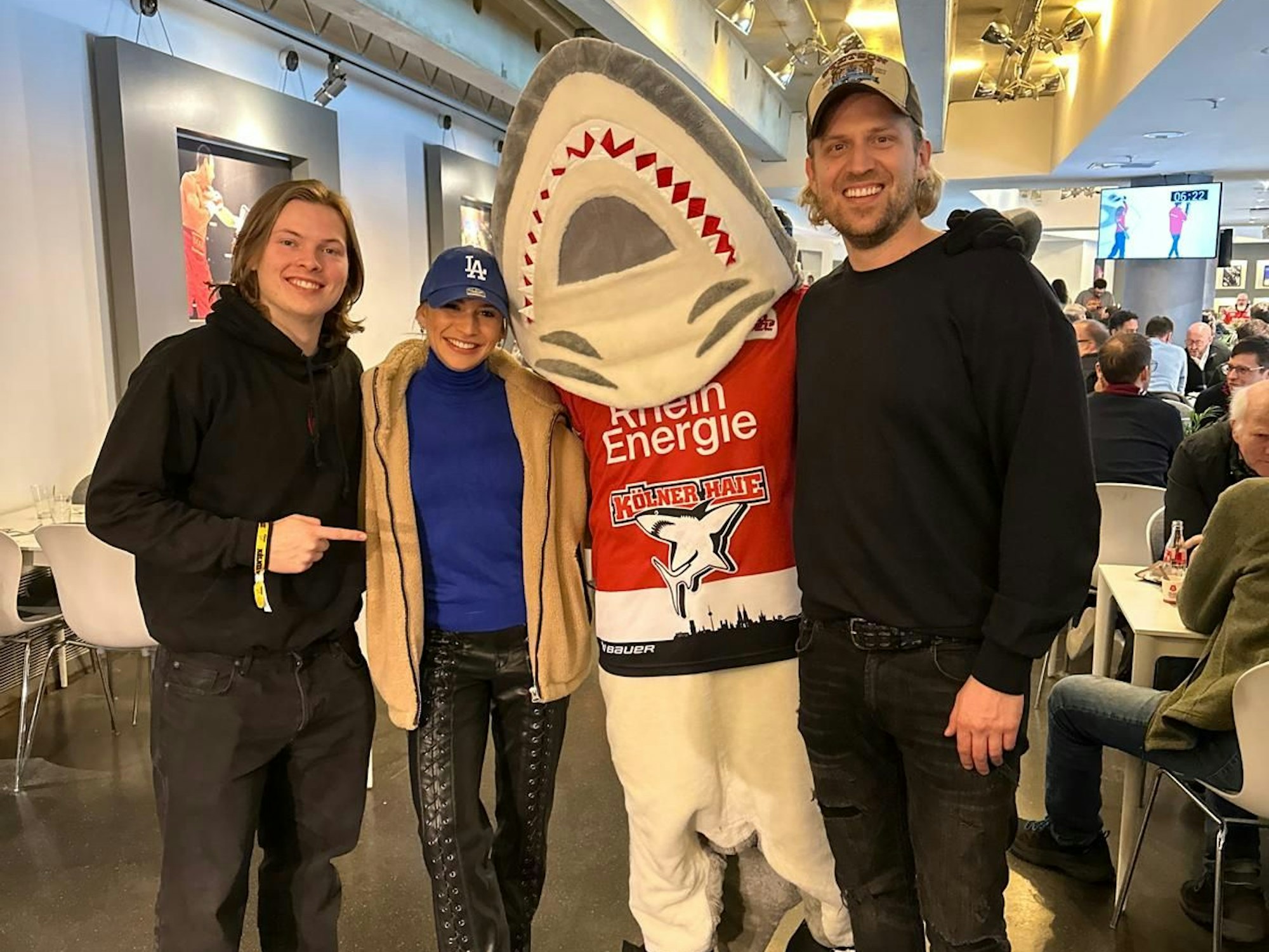 Gabriel Kelly (l.), Jana Wosnitza und Tillman Schulz trafen am 21. Februar 2024 beim Spiel der Kölner Haie auf Maskottchen Sharky.