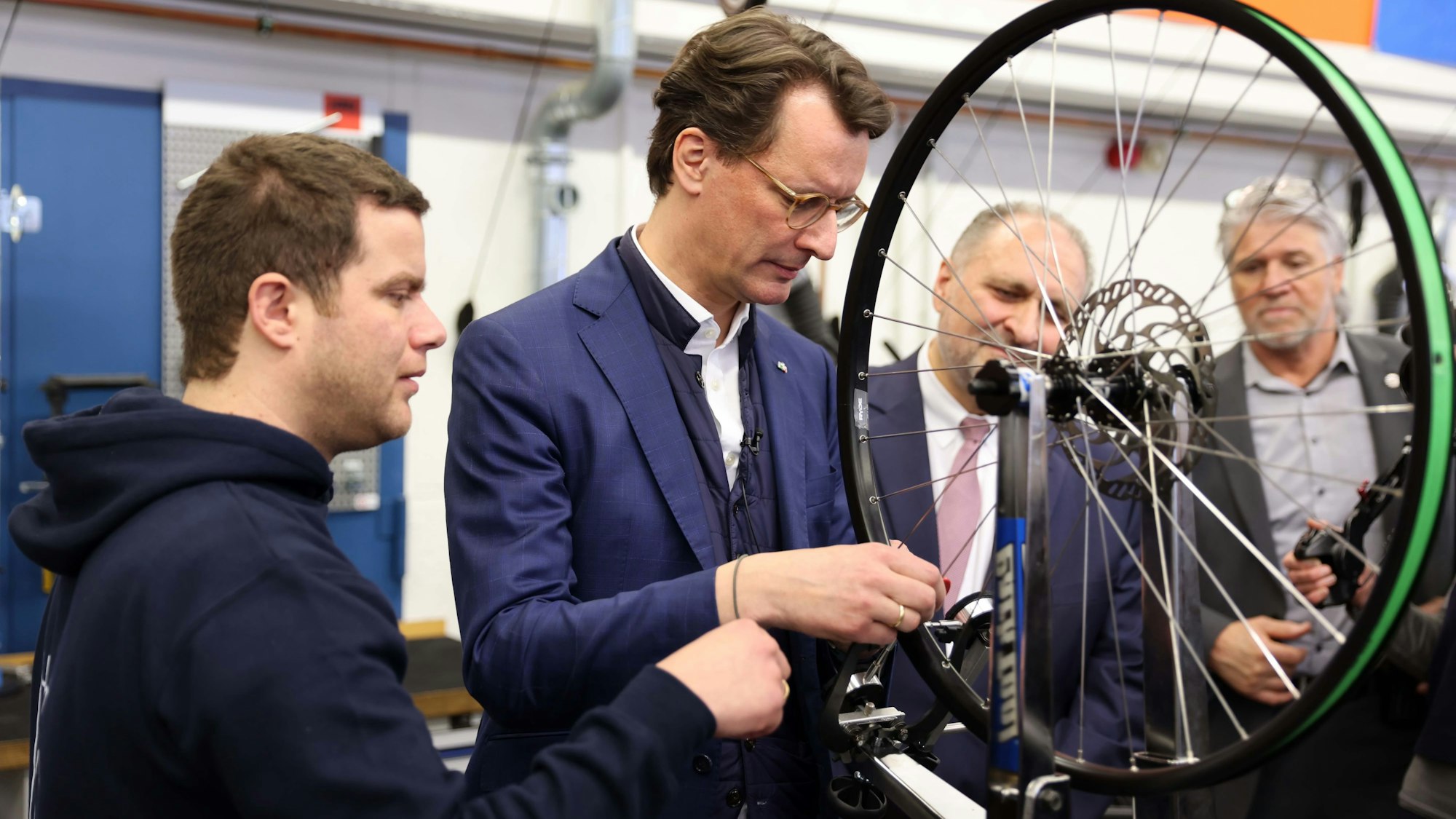 Wüst richtete auf dem HWK-Ausbildungscampus einen Fahrradreifen neu aus, unter genauer Begutachtung von Sebastian Hüsch.