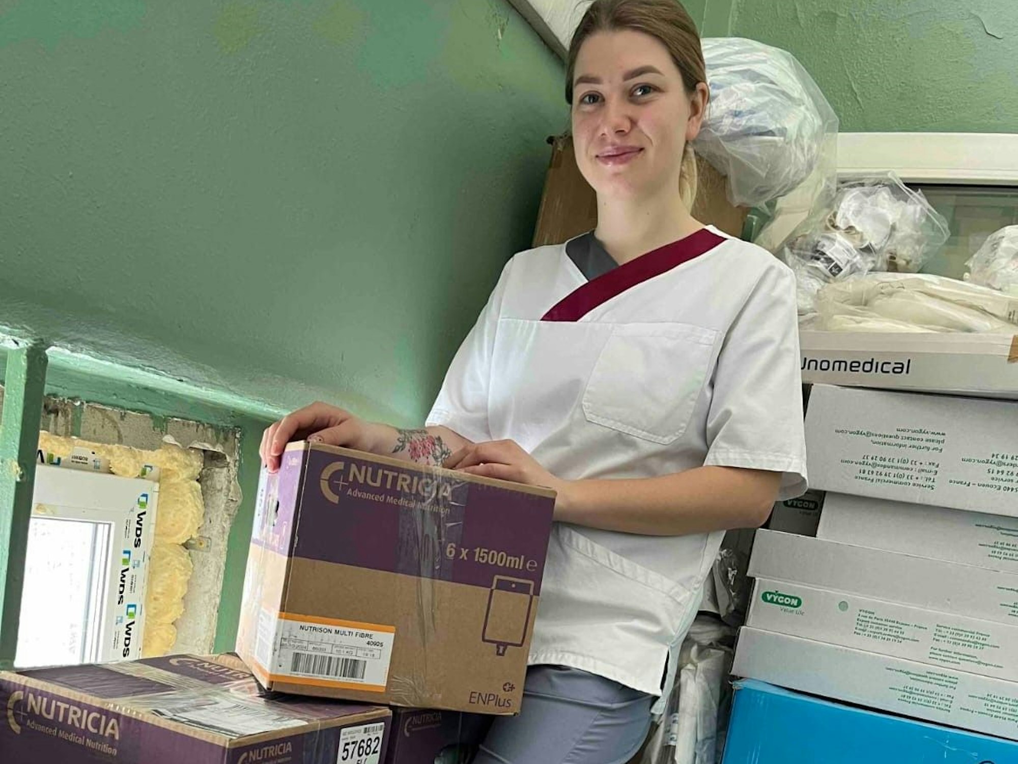 Eine junge Krankenschwester aus der Ukraine steht neben zehn Kisten mit Hilfsmitteln.