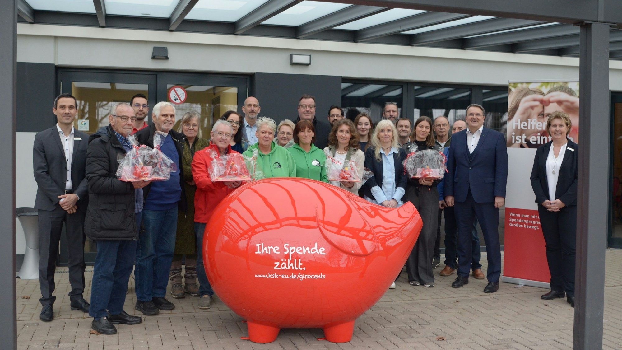 Vertreter von Vereinen und Kreissparkasse stehen für ein Gruppenfoto hinter einem überdimensionalen roten Sparschwein mit der Aufschrift „Ihre Spende zählt“.