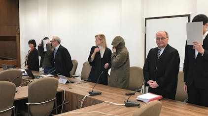 Zu sehen sind drei Angeklagte und ihre Anwälte in einem Kölner Gerichtssaal.
