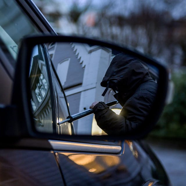 Ein Mann versucht, eine Autotür mit einer Metallstange aufzubrechen (gestellte Szene).&nbsp;